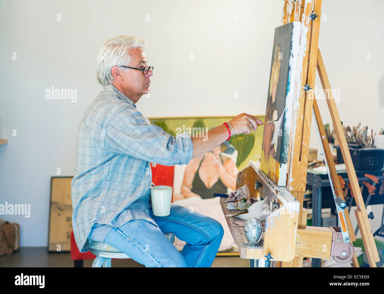 Older Hispanic artist painting in studio Stock Photo