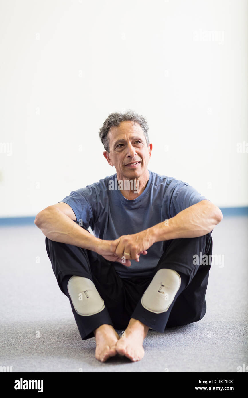 Senior Caucasian man sitting on floor Stock Photo