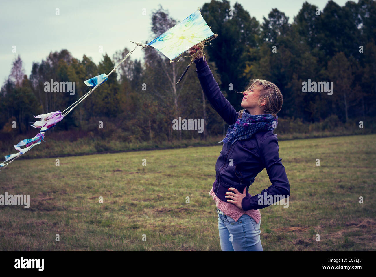 Woman flying kite in field Stock Photo