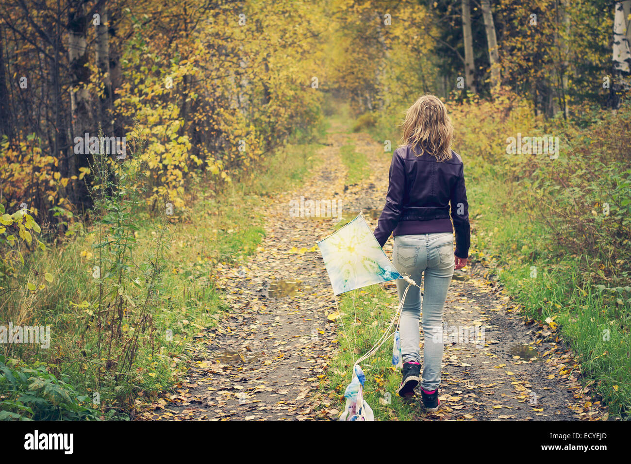 Woman carrying kite on dirt path Stock Photo
