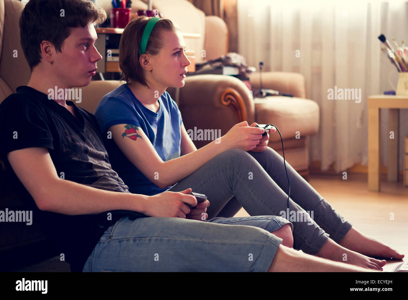 Couple playing video games on living room floor Stock Photo