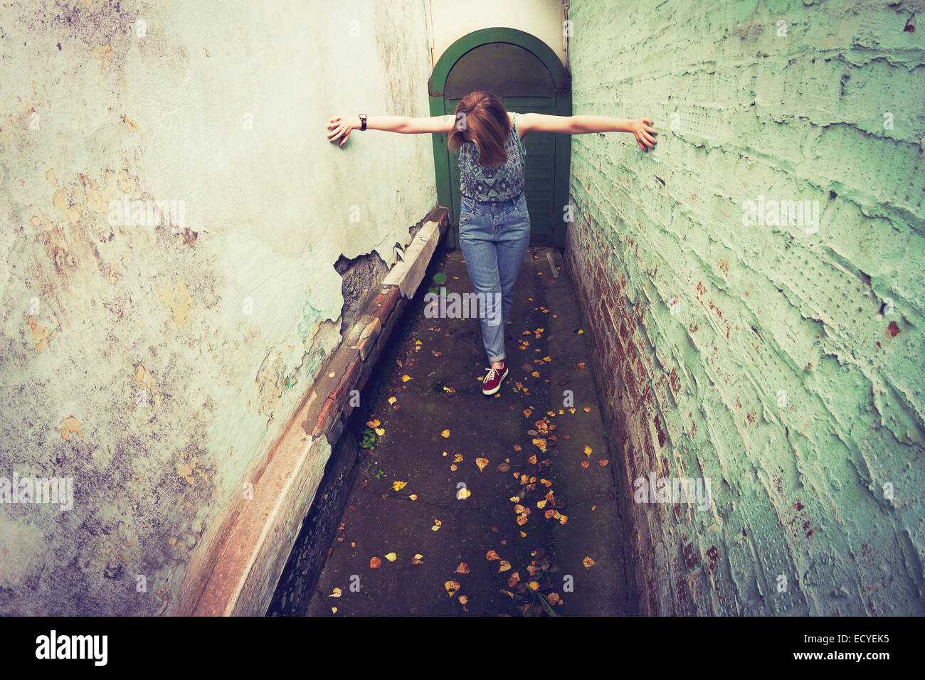 Woman touching walls in alley Stock Photo