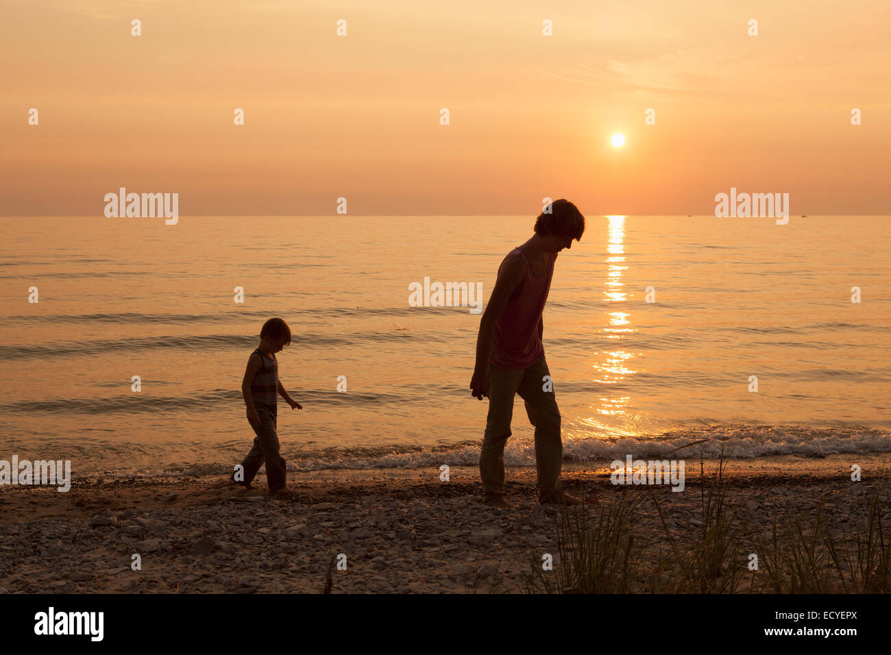 Caucasian brothers walking on beach at sunset Stock Photo