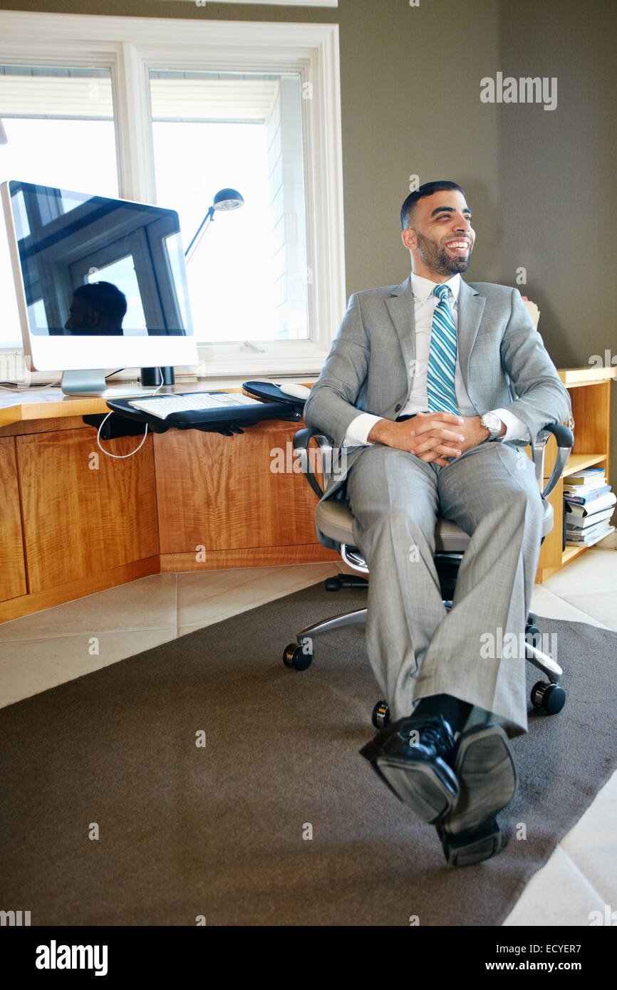 Middle Eastern businessman relaxing in chair at desk in office Stock Photo