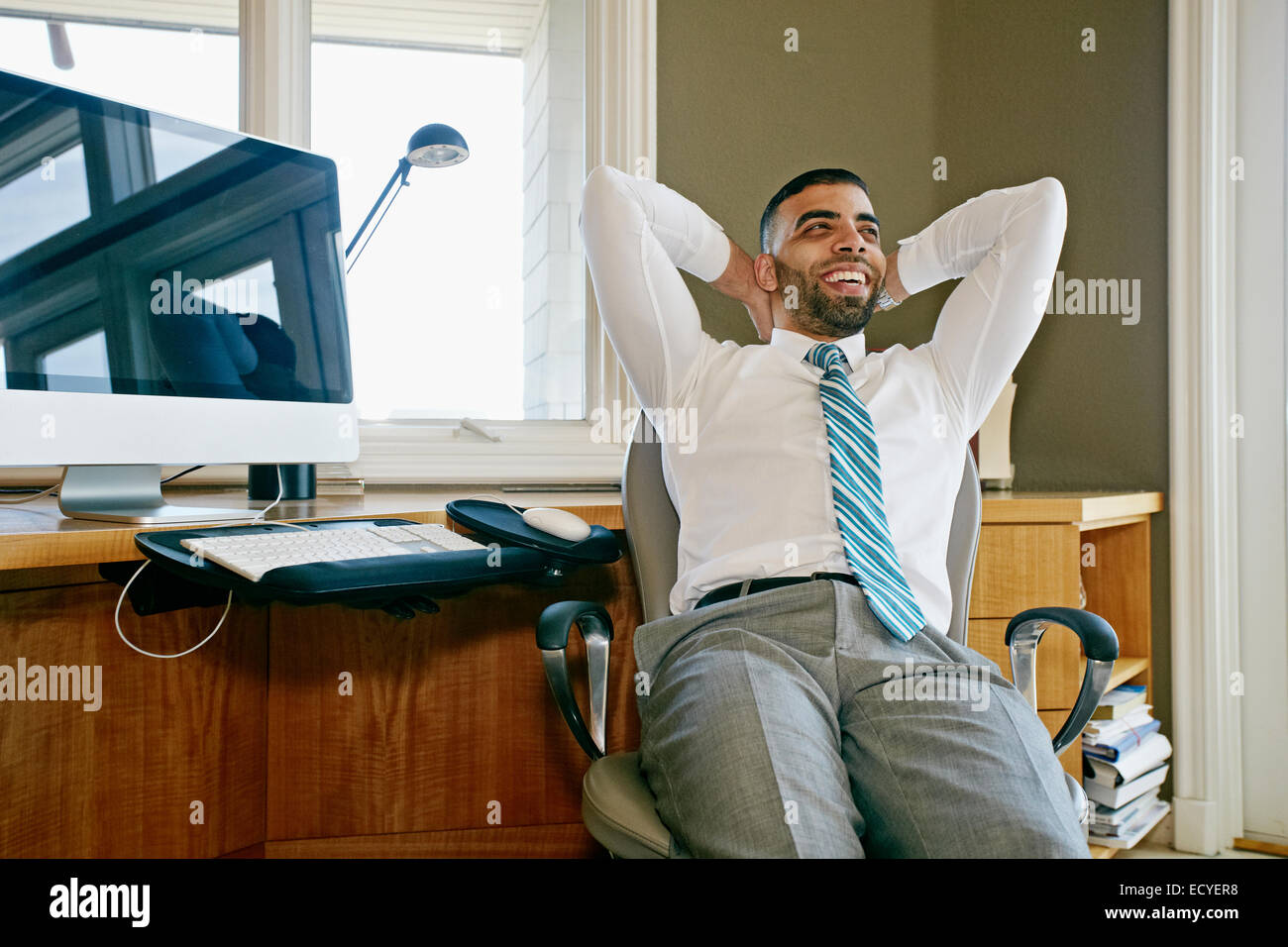 Middle Eastern businessman relaxing in chair at desk in office Stock Photo