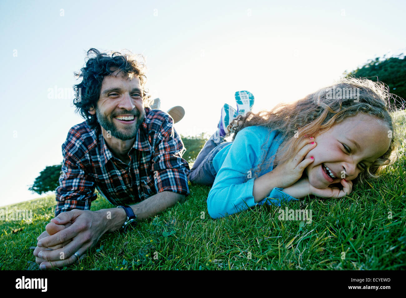 Father and daughter playing in grassy field Stock Photo