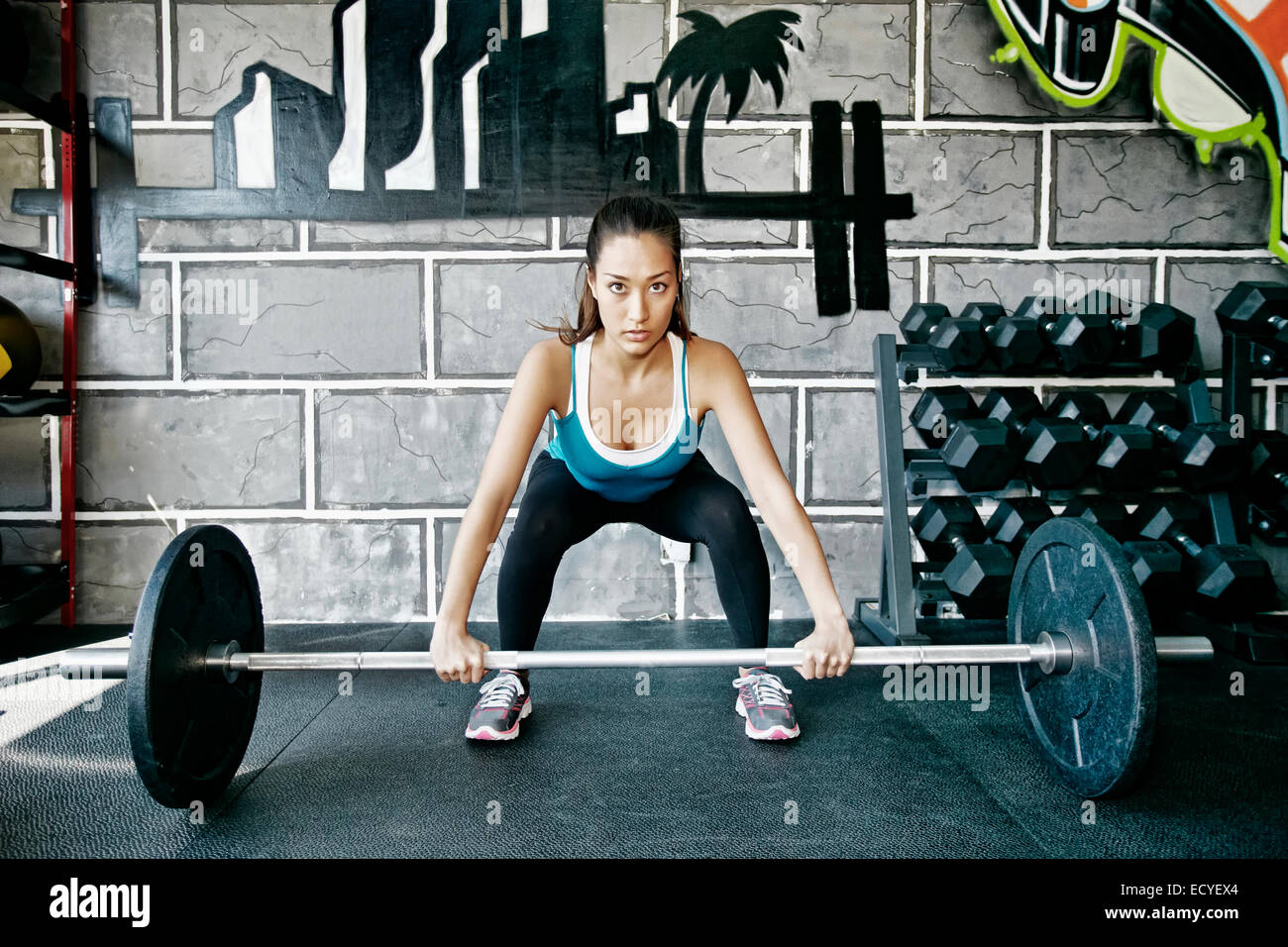 Mixed race woman lifting weights in gym Stock Photo