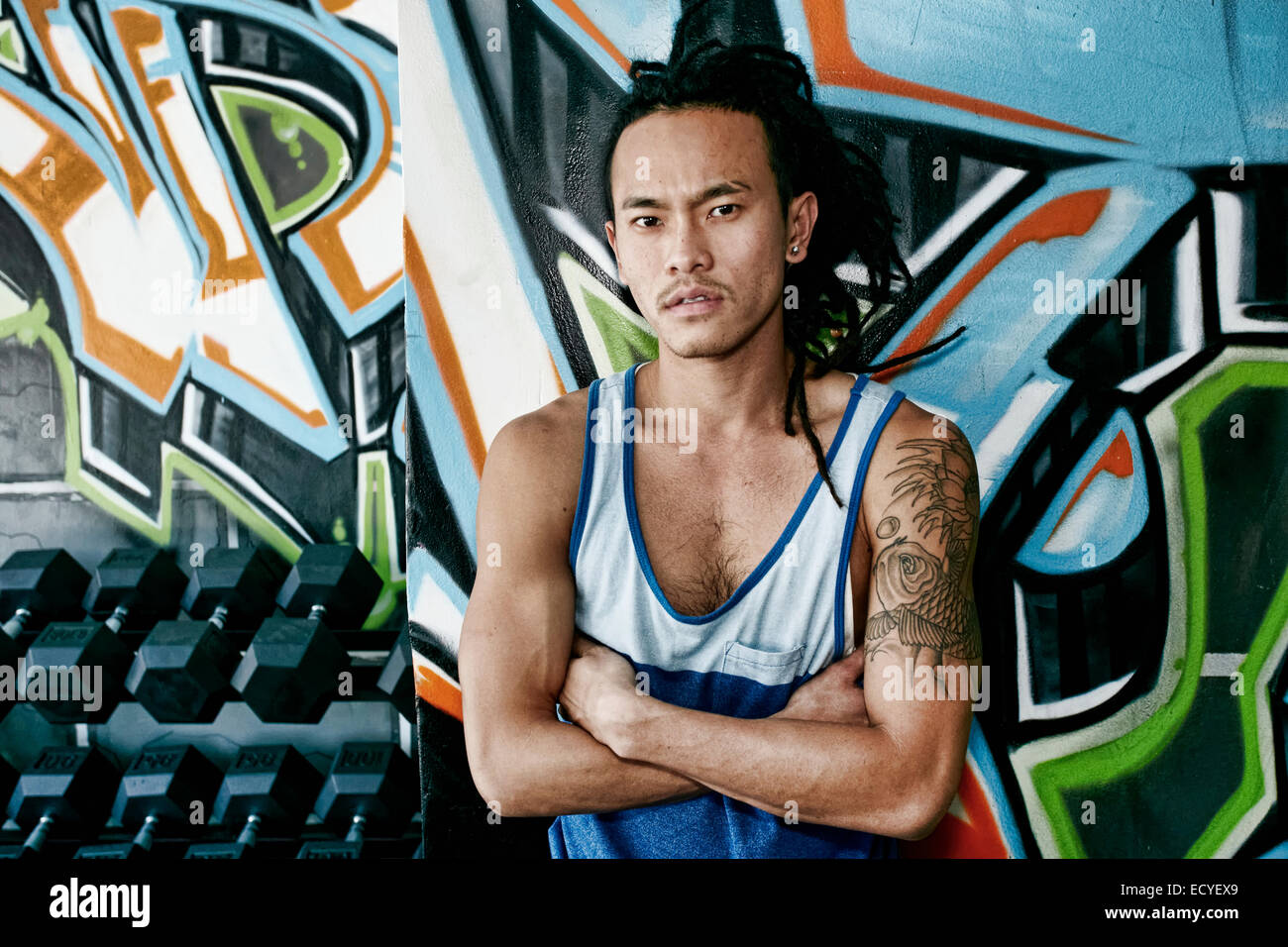 Asian man standing with arms crossed in gym Stock Photo