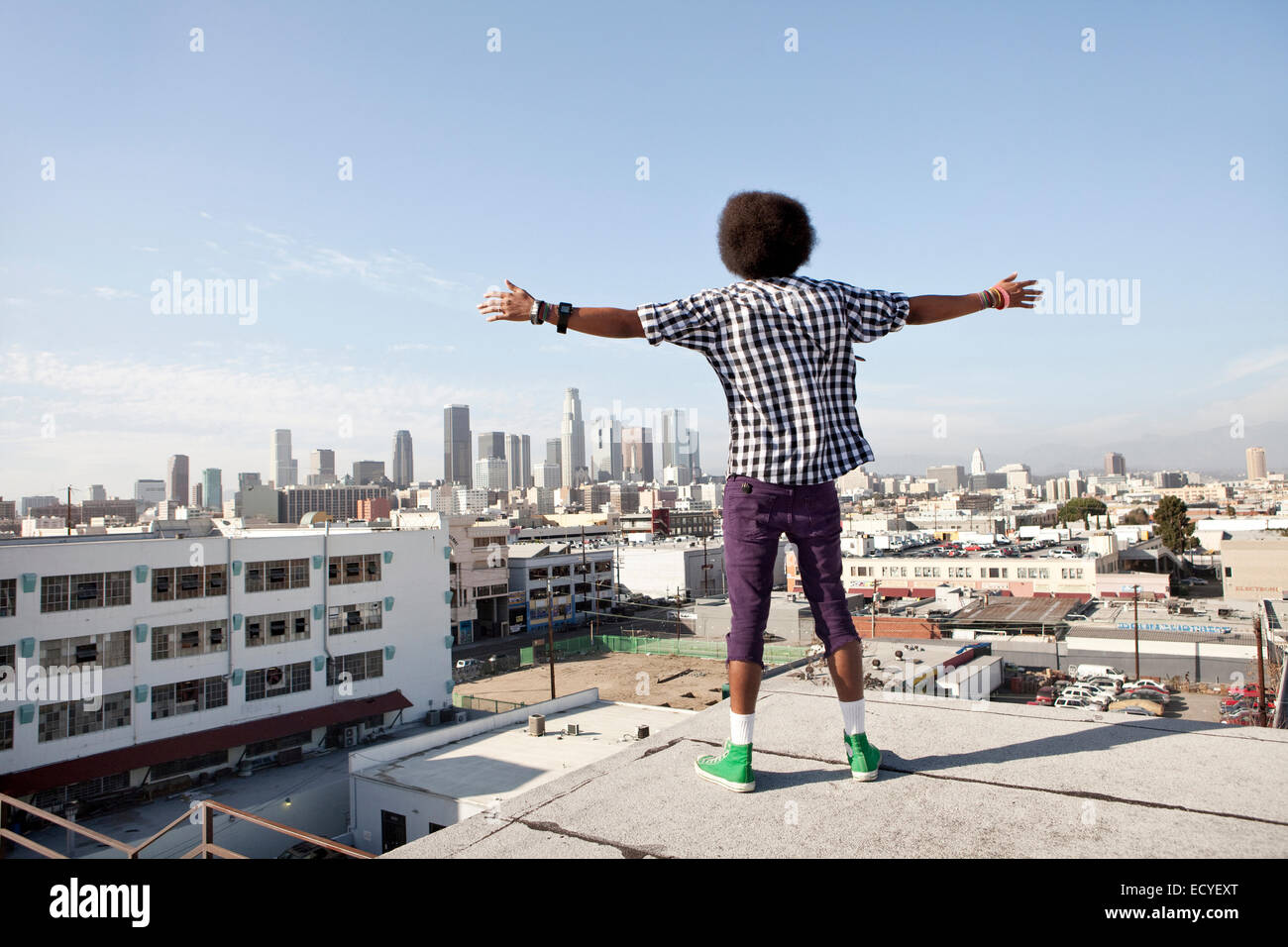 African American man overlooking cityscape from urban rooftop Stock Photo