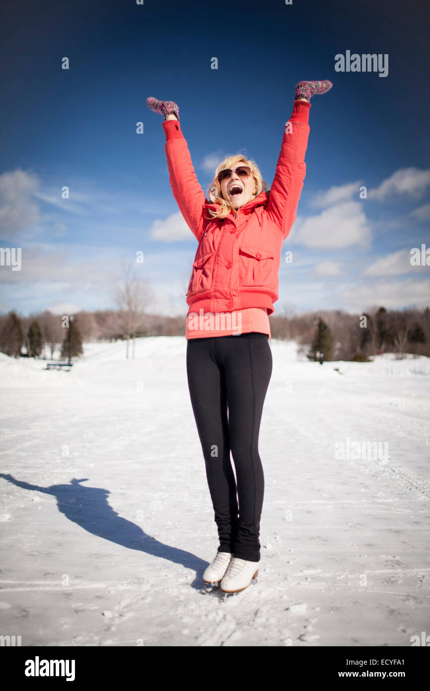 Caucasian woman on ice skates cheering on frozen lake Stock Photo