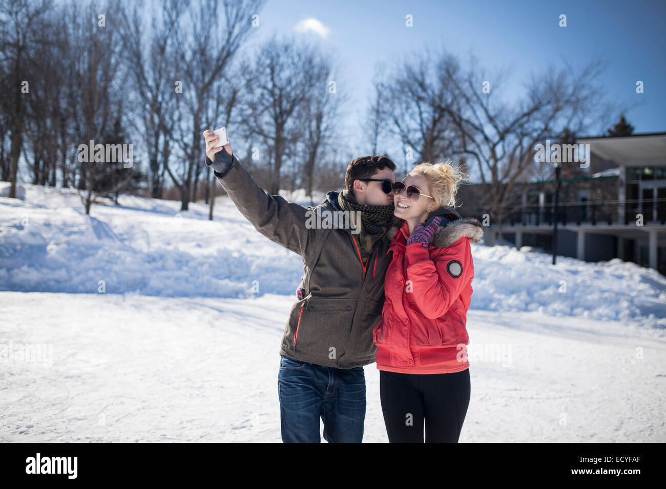 Caucasian couple taking cell phone selfie in winter Stock Photo