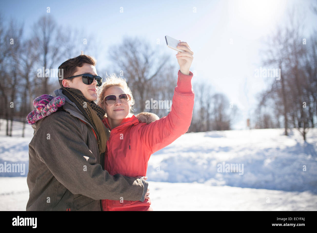 Caucasian couple taking cell phone selfie in winter Stock Photo