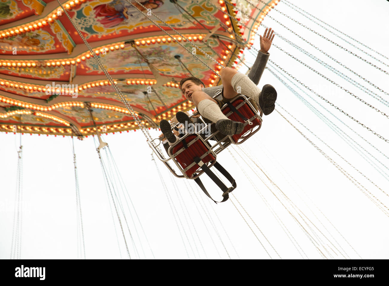 german man boy flying swing chair ride theme park munich oktoberfest Stock Photo