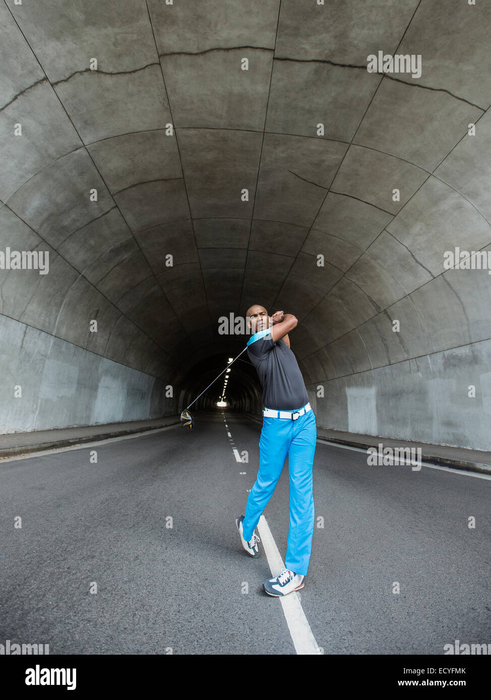 Black man playing golf in urban tunnel Stock Photo