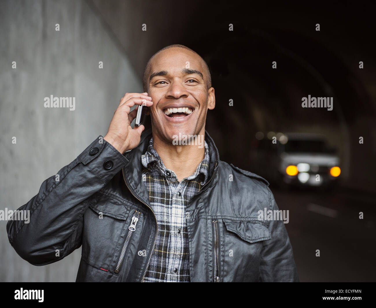 Black man talking on cell phone in urban tunnel Stock Photo