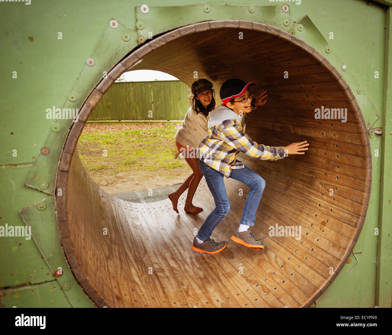 Mixed race children playing in wheel in playground Stock Photo