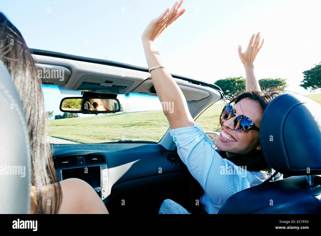 Excited women driving convertible on road trip Stock Photo