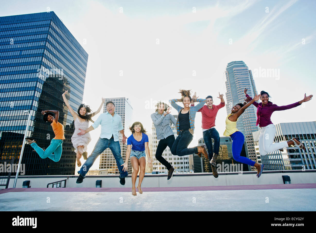 Friends jumping for joy on urban rooftop Stock Photo