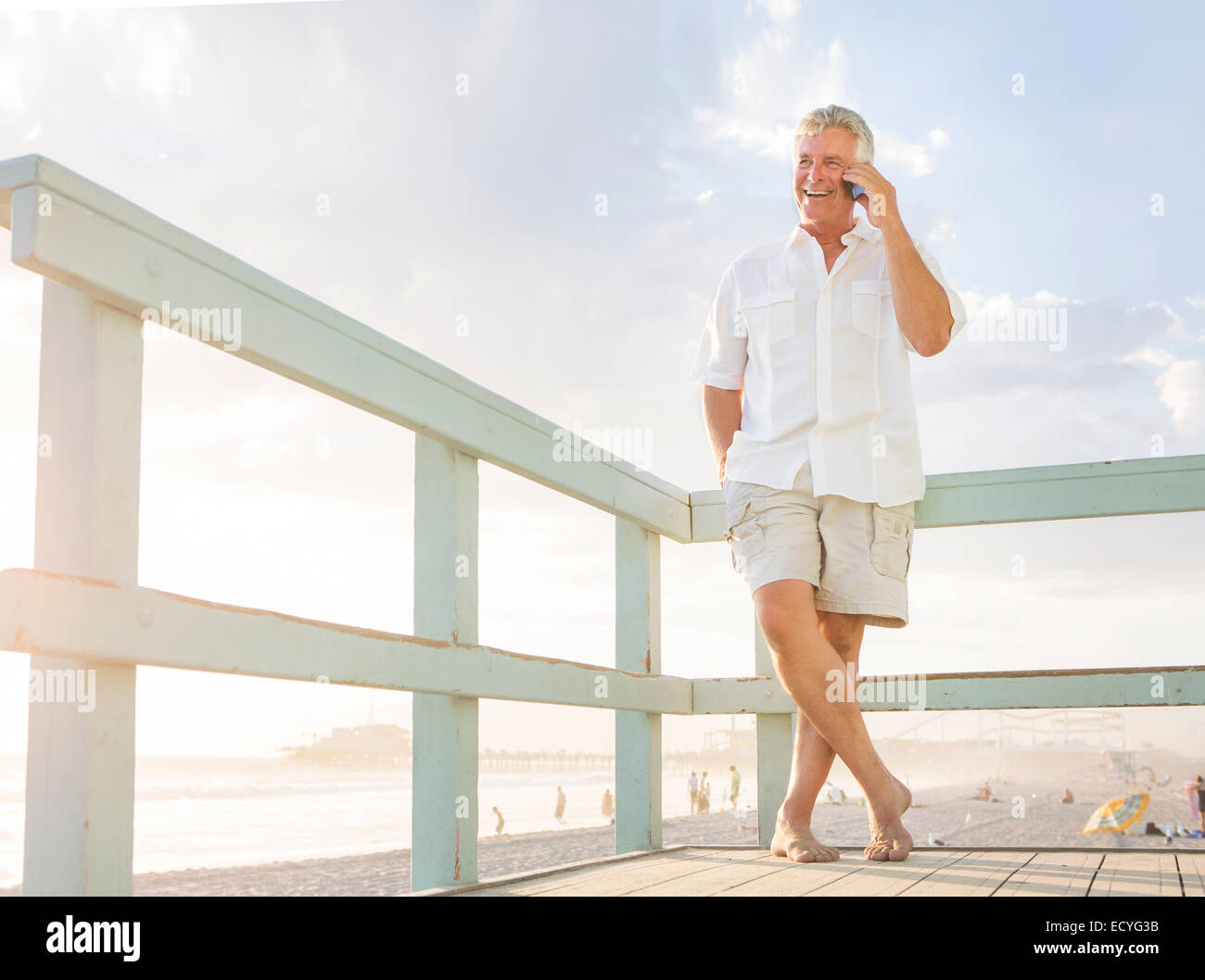 Caucasian man talking on cell phone on boardwalk at beach Stock Photo