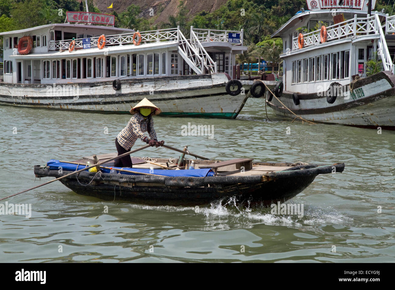 Woman rowing a small boat in Ha Long Bay, Vietnam. Stock Photo