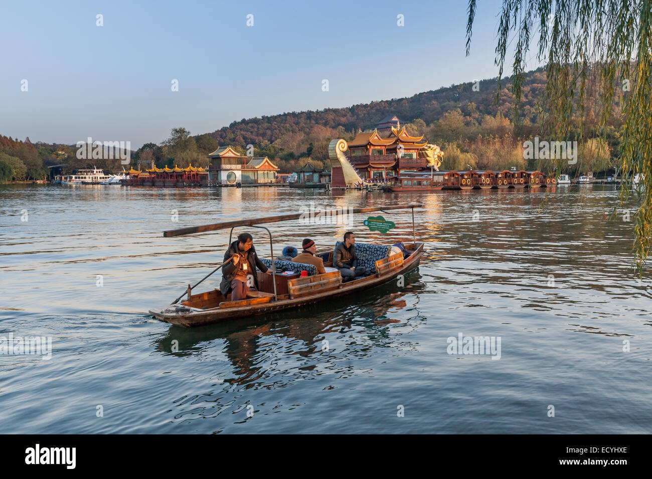 Hangzhou, China - December 5, 2014: Traditional Chinese wooden recreation boat with boatman floats on the West Lake. Famous park Stock Photo