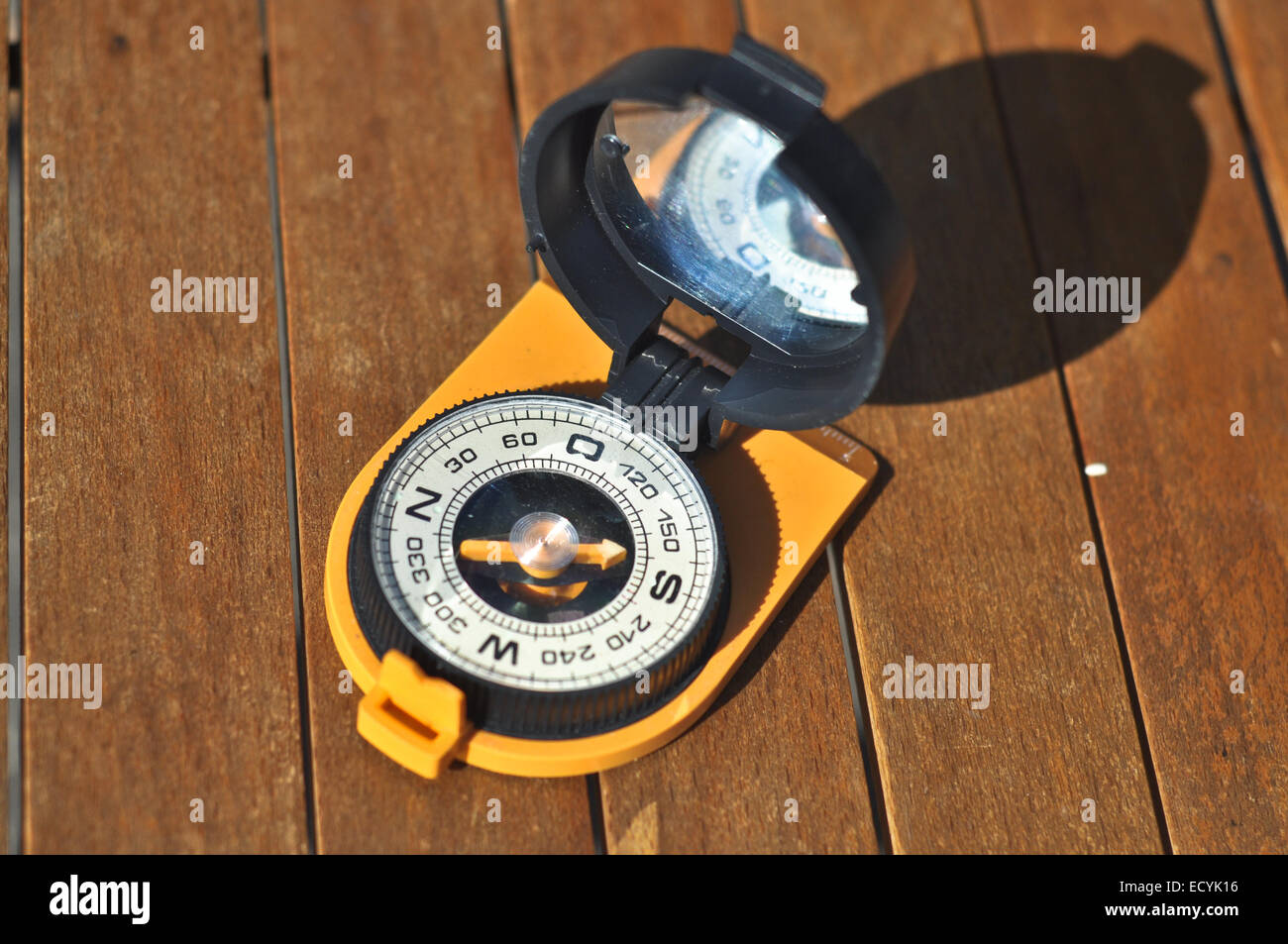 The compass on the boards. The magnetic compass lies on brown boards under the sun. Stock Photo
