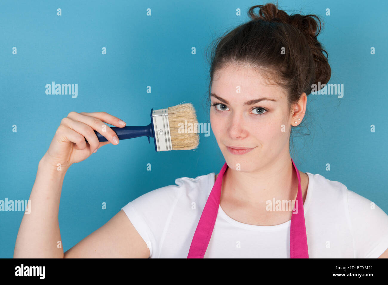 Woman with apron and paint brush against blue wall Stock Photo Alamy