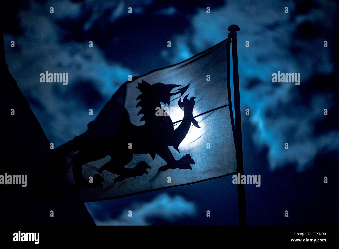 A full moon shining through a Welsh national  flag banner, showing the moonlit red dragon emblem of Wales in silhouette, Wales UK Stock Photo