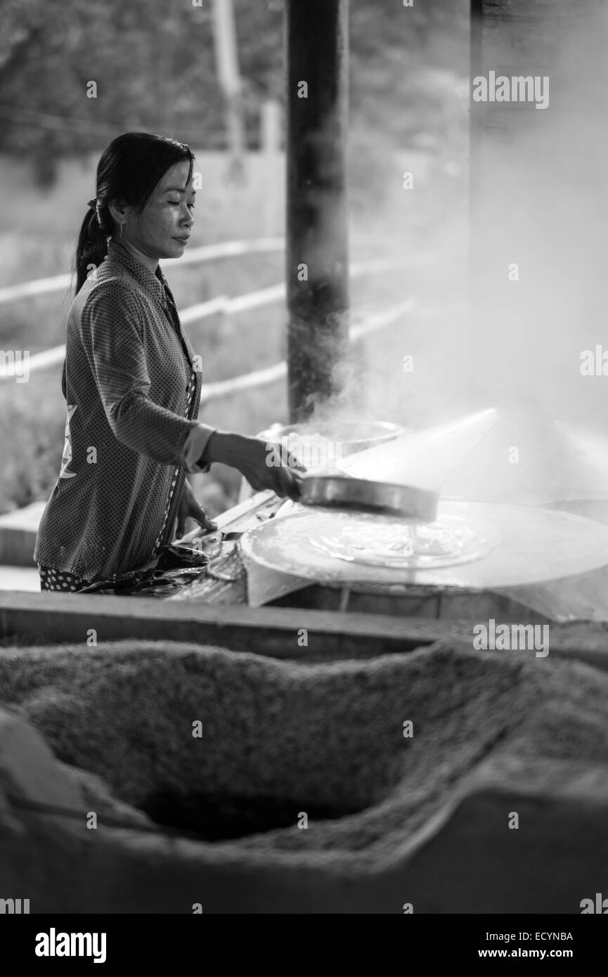 Young Vietnamese woman cooking rice paper in the small home factory that her family owns in the Mekong Delta of Vietnam. Stock Photo