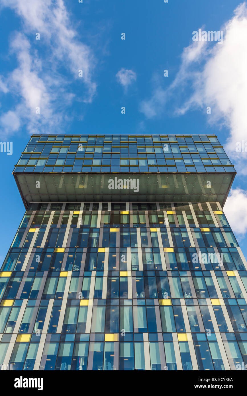 Modern office building with glass facade against a blue sky with white ...