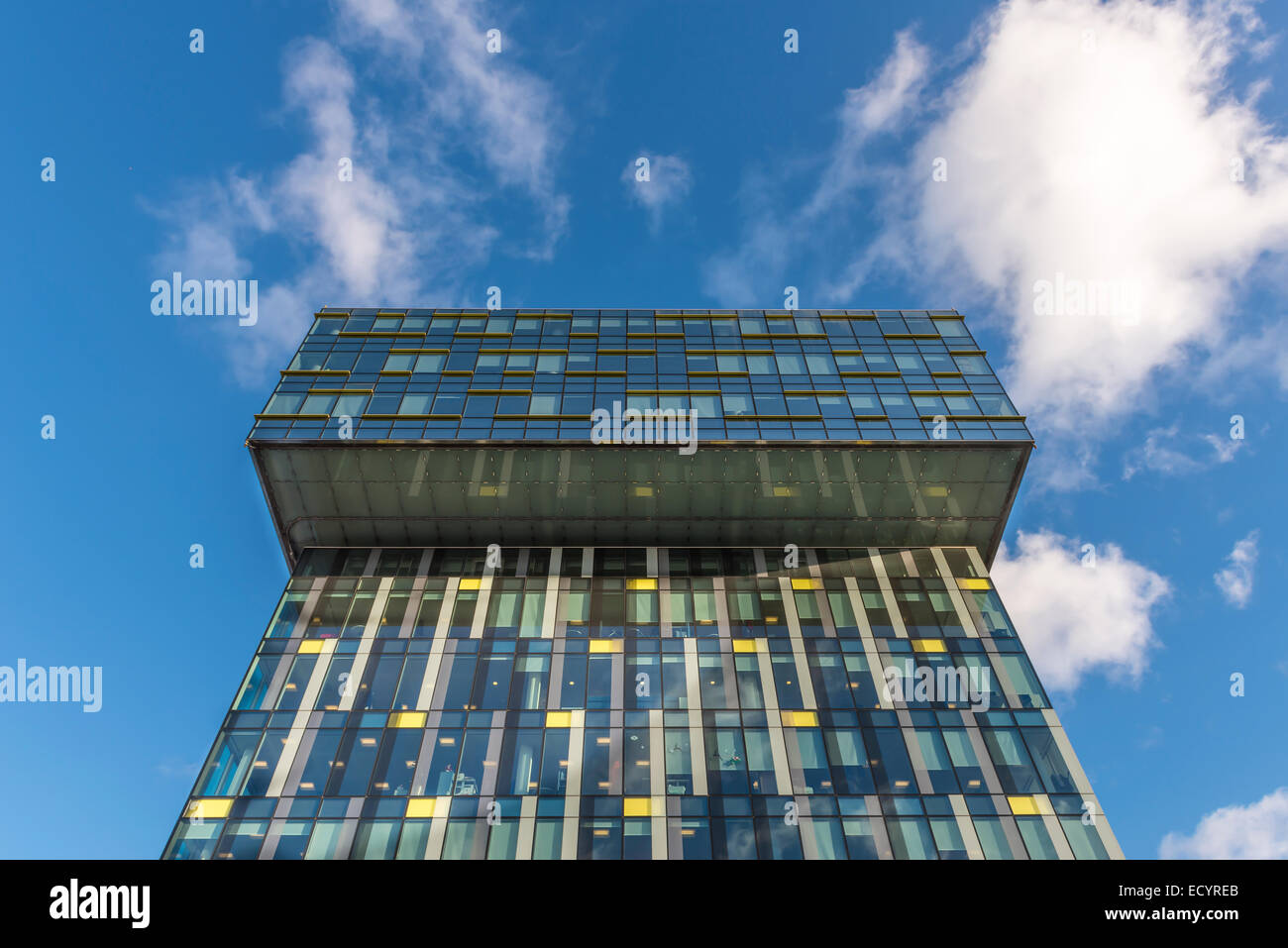 Modern office building with glass facade against a blue sky with white ...