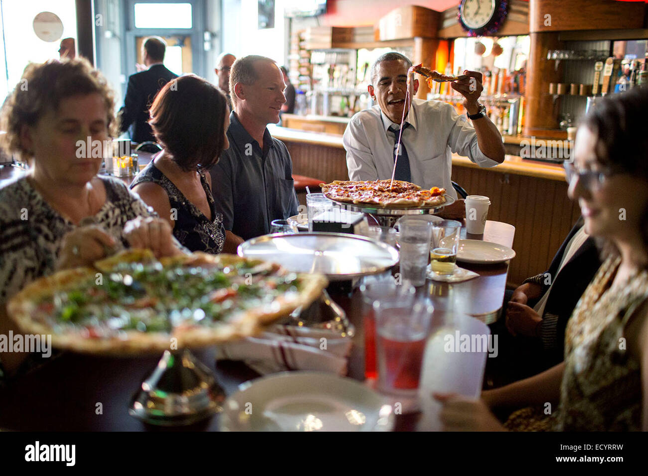 President Barack Obama shares a pizza dinner with individuals who wrote letters to him, at the Wazee Supper Club in Denver, Colo., July 8, 2014. Stock Photo