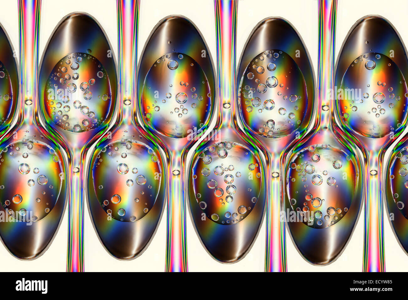 Polarized stress patterns in row of plastic spoons with carbonated liquids from above Stock Photo