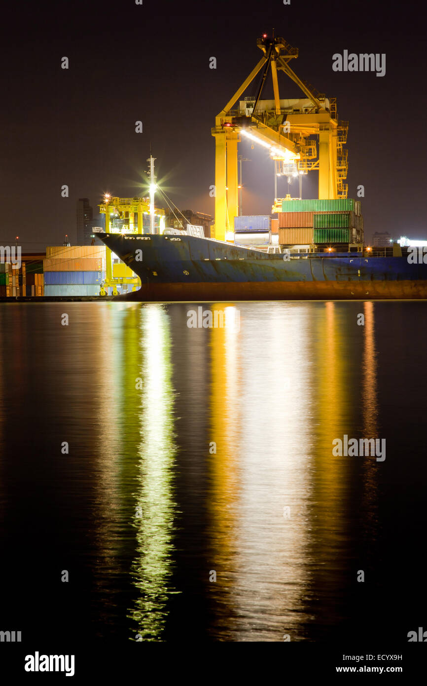 Industrial Container Cargo freight ship with working crane bridge in shipyard at dusk for Logistic Import Export background Stock Photo