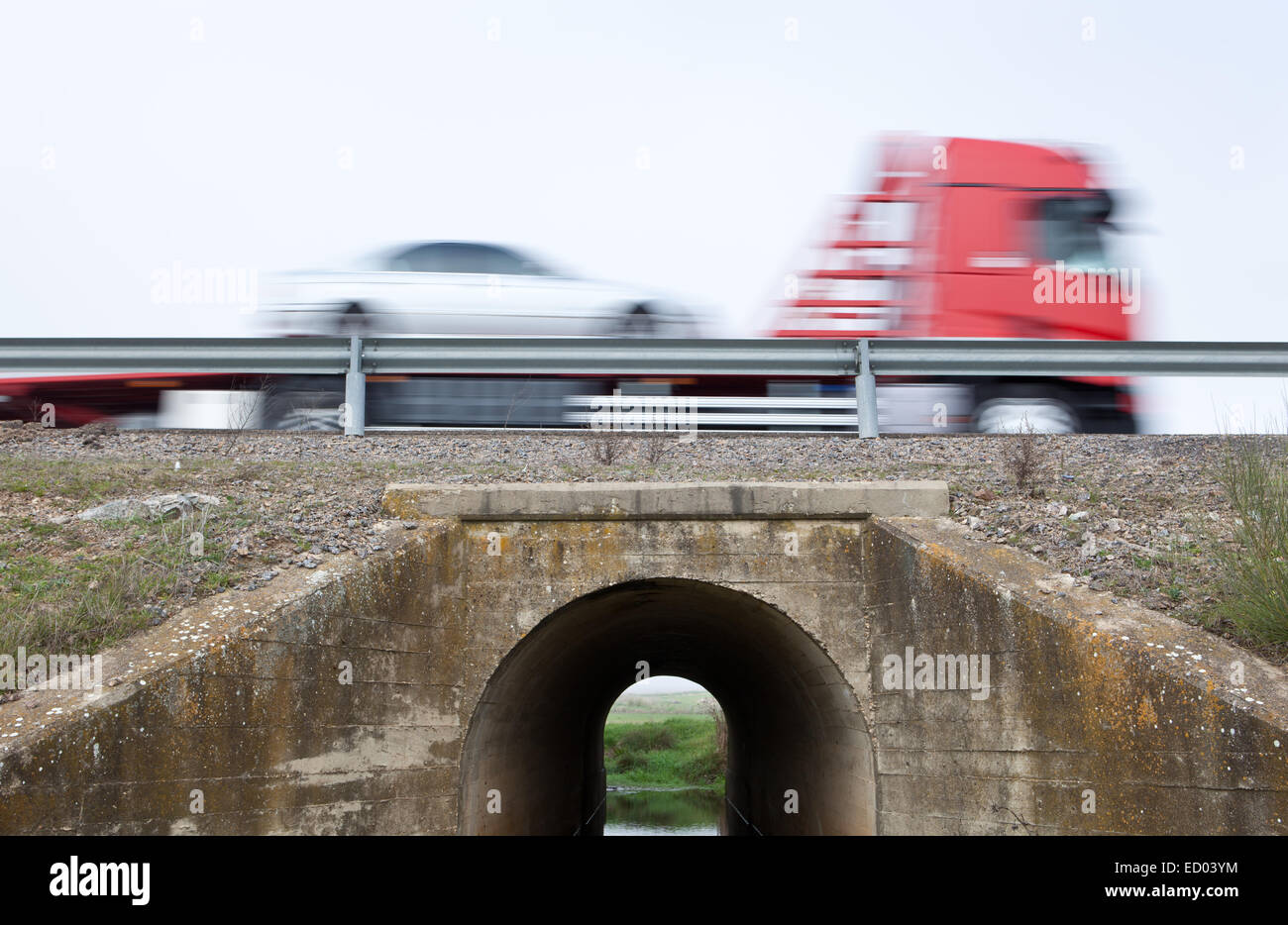 Truck transports cars in motion crossing a canal bridge Stock Photo