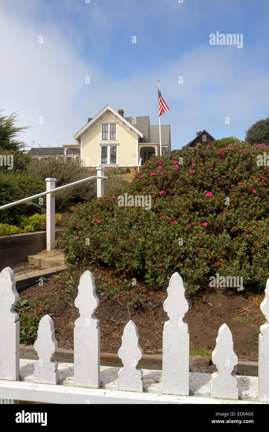 Looking over a white picket fence towards the Kelley House Museum in the town of Mendocino, California Stock Photo