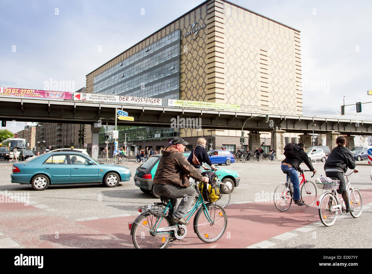 People riding a bike in Warschauer strasse, in front of Universal Studies, Berlin, Germany Stock Photo