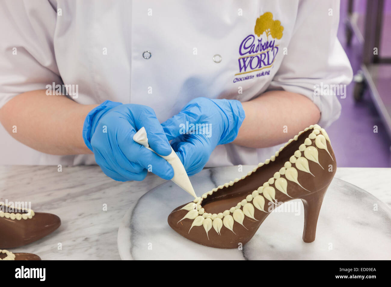 England, Birmingham, Bournville, Cadbury World, Woman Decorating Chocolate Shoe Stock Photo