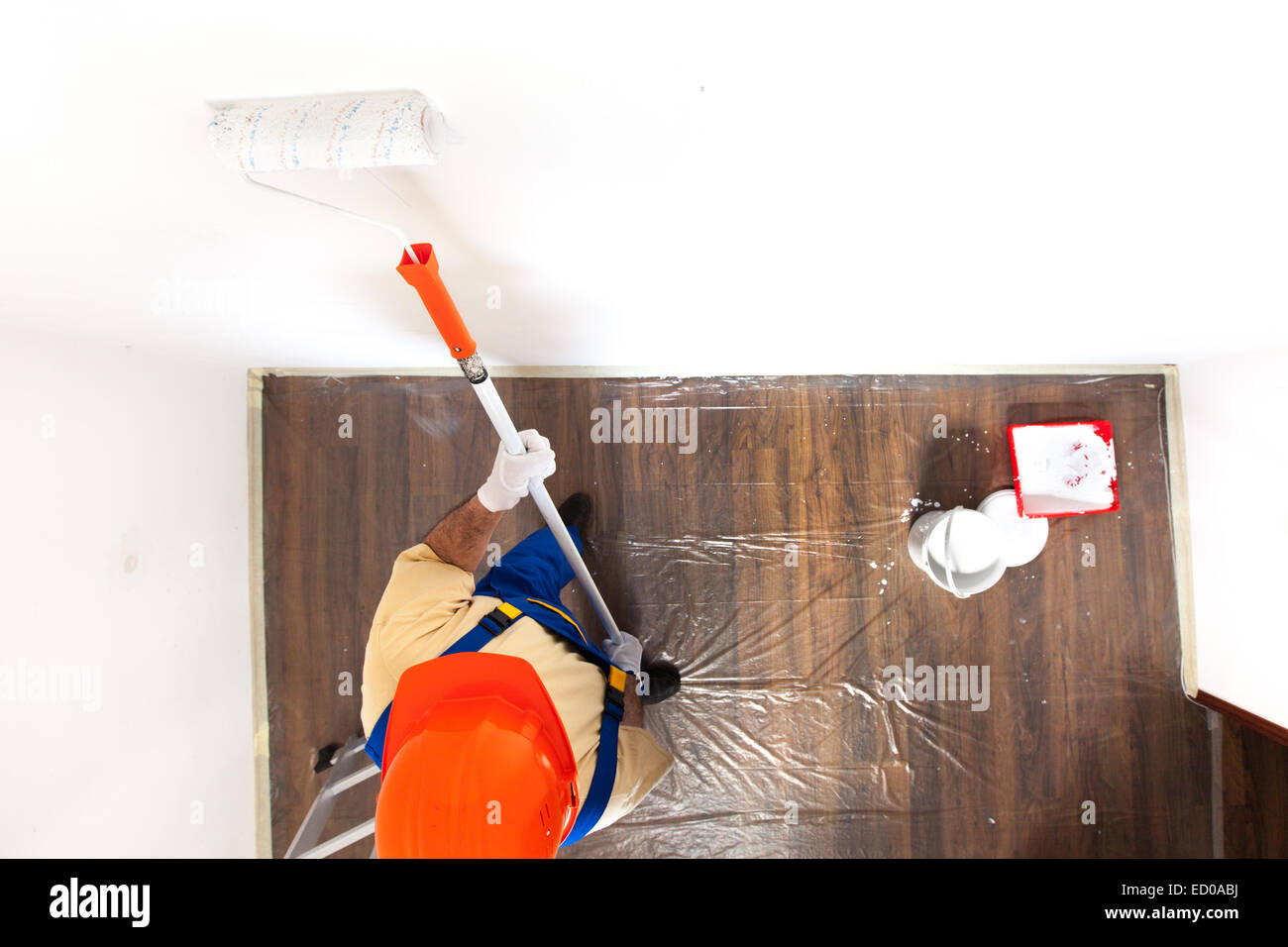 Man is painting a wall in white by paint roller. Stock Photo