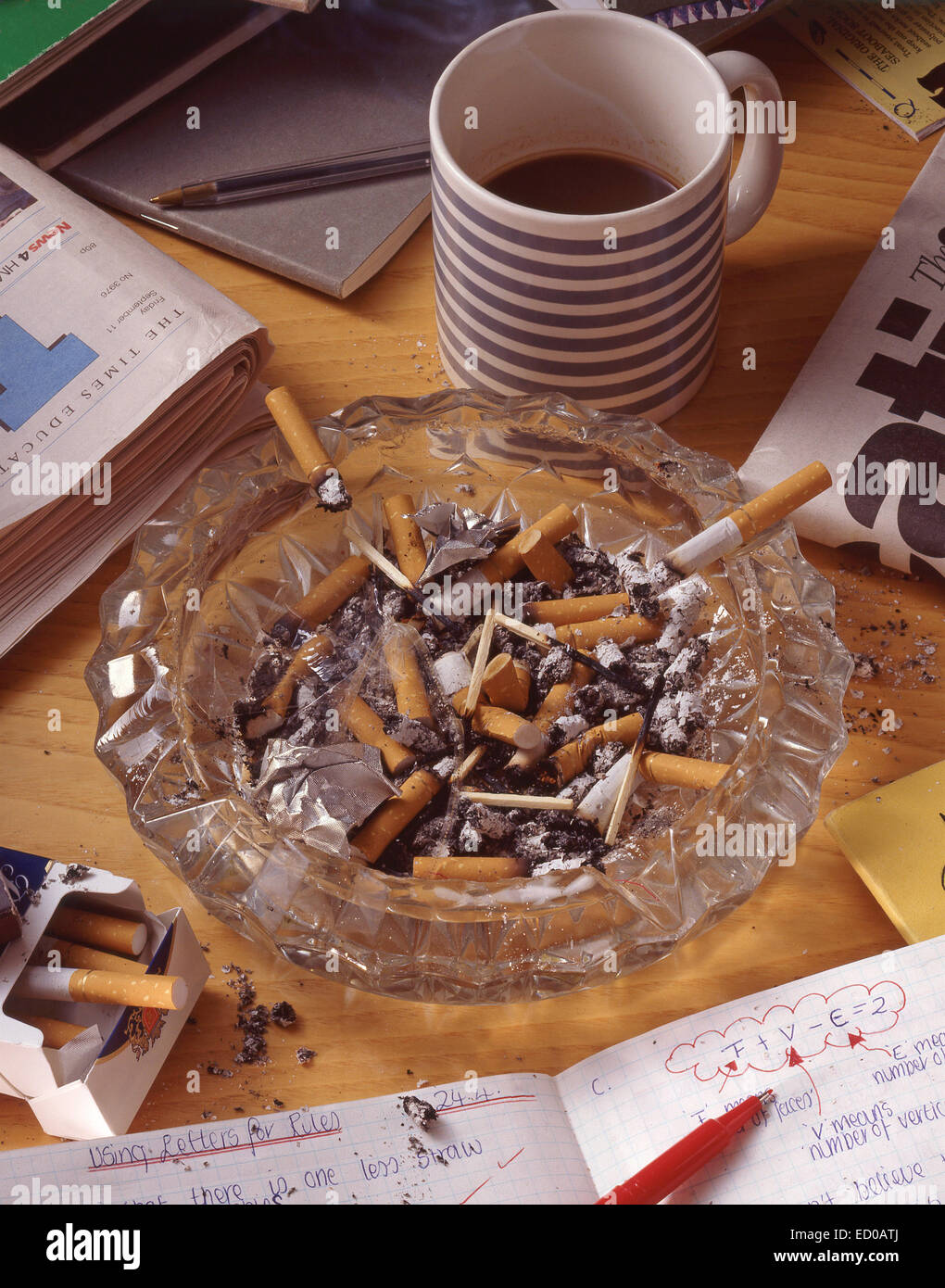Work desk showing ashtray filled with cigarette butts Stock Photo
