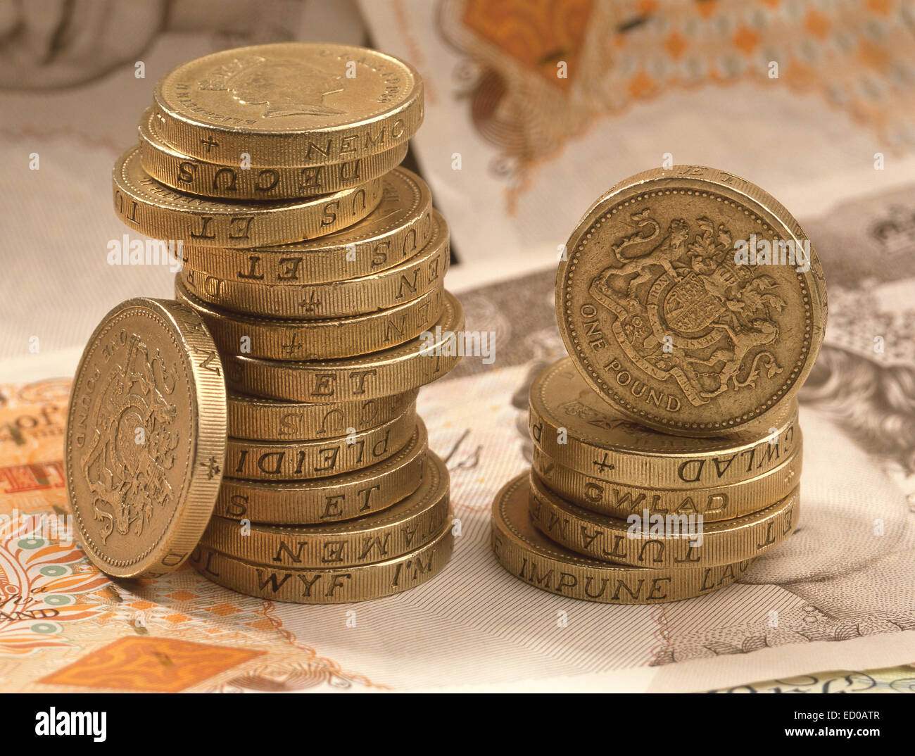 Pile of British one pound coins with background of £10 English banknotes Stock Photo