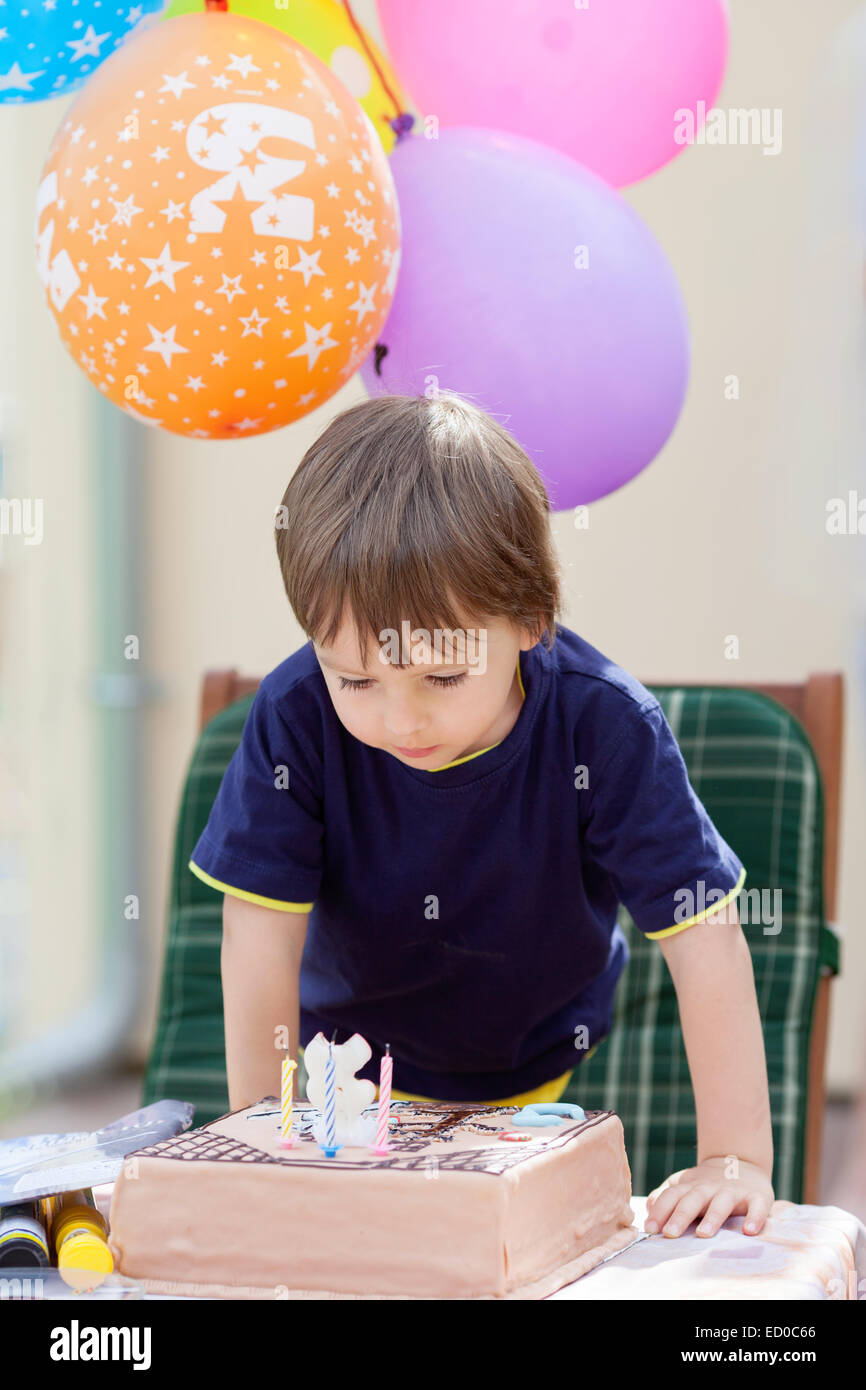 Boy blowing out candles on his birthday cake Stock Photo