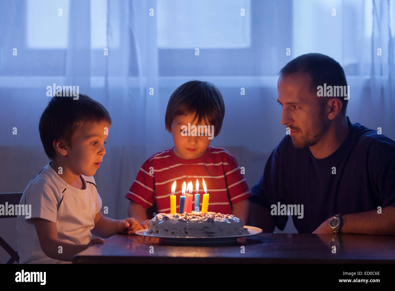 Boy about to blow out candles on his birthday cake with his father and