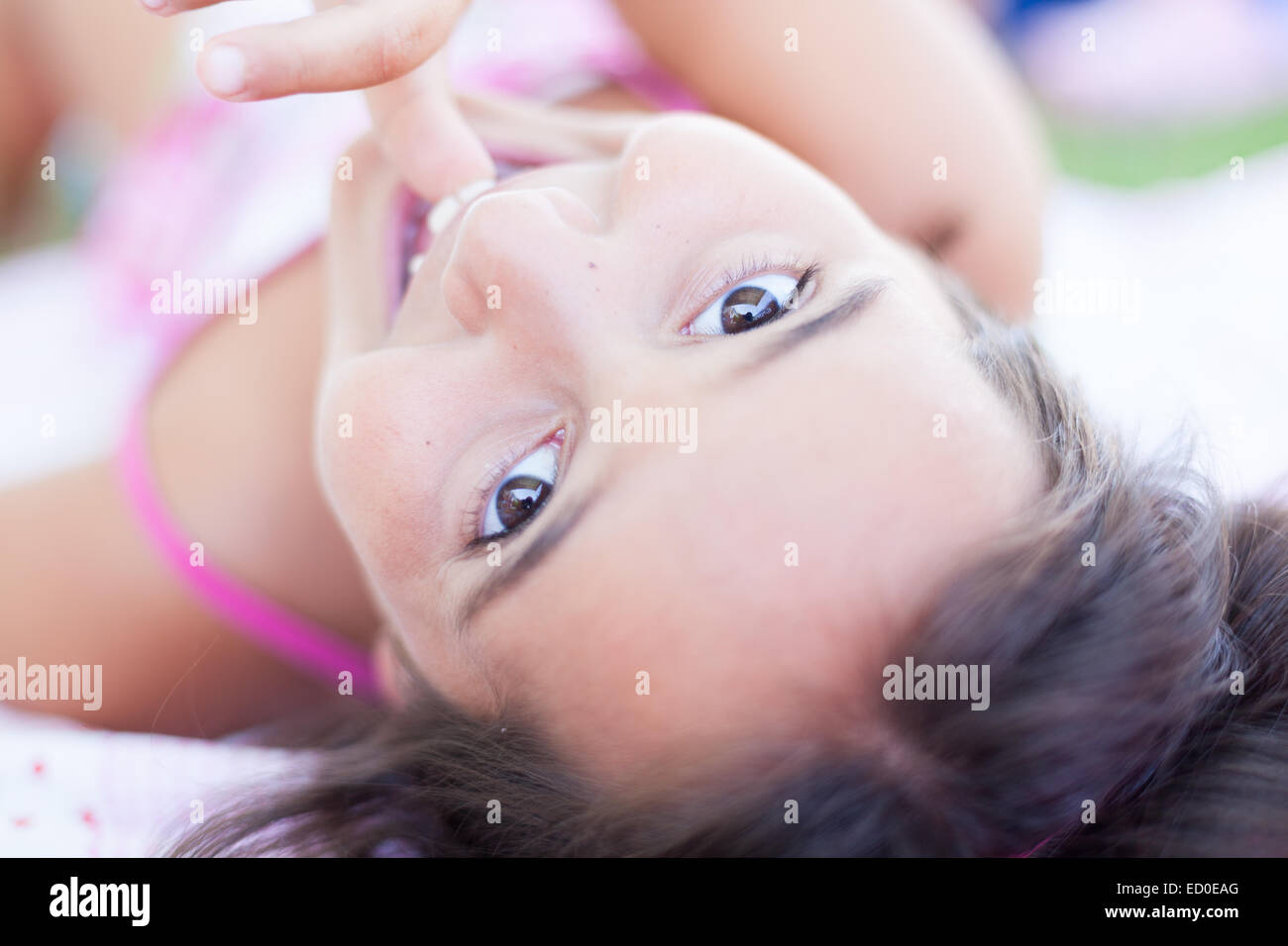 Close-up portrait of a smiling girl sucking her thumb Stock Photo