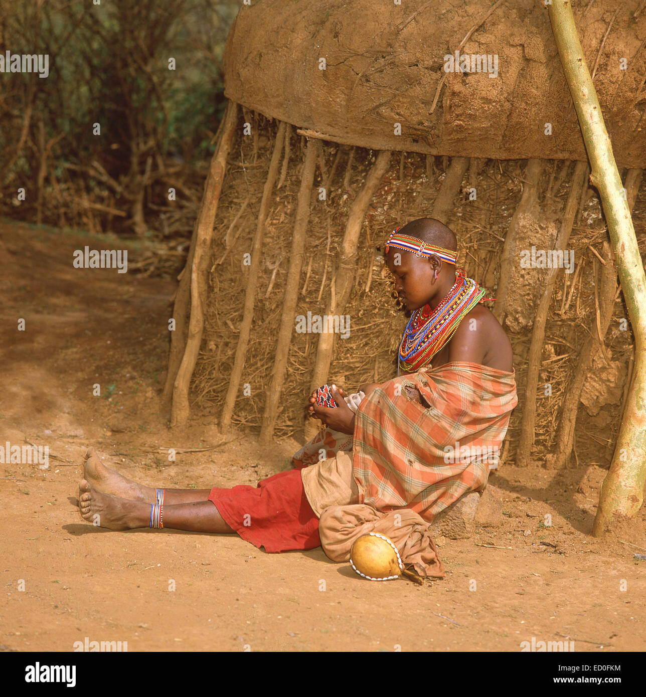 Maasai girl making colourful necklace, The Maasai Mara National Reserve, Narok County, Kenya Stock Photo