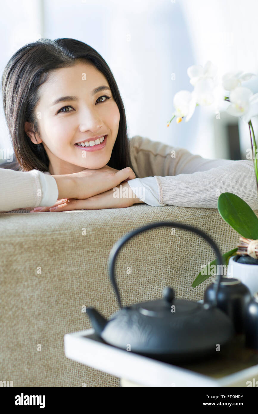 Happy young woman sitting on sofa Stock Photo - Alamy