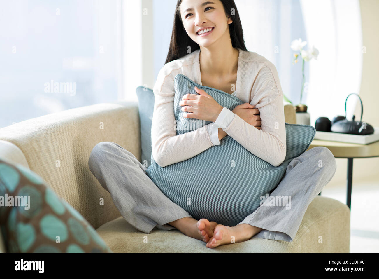 Happy young woman sitting on sofa Stock Photo - Alamy