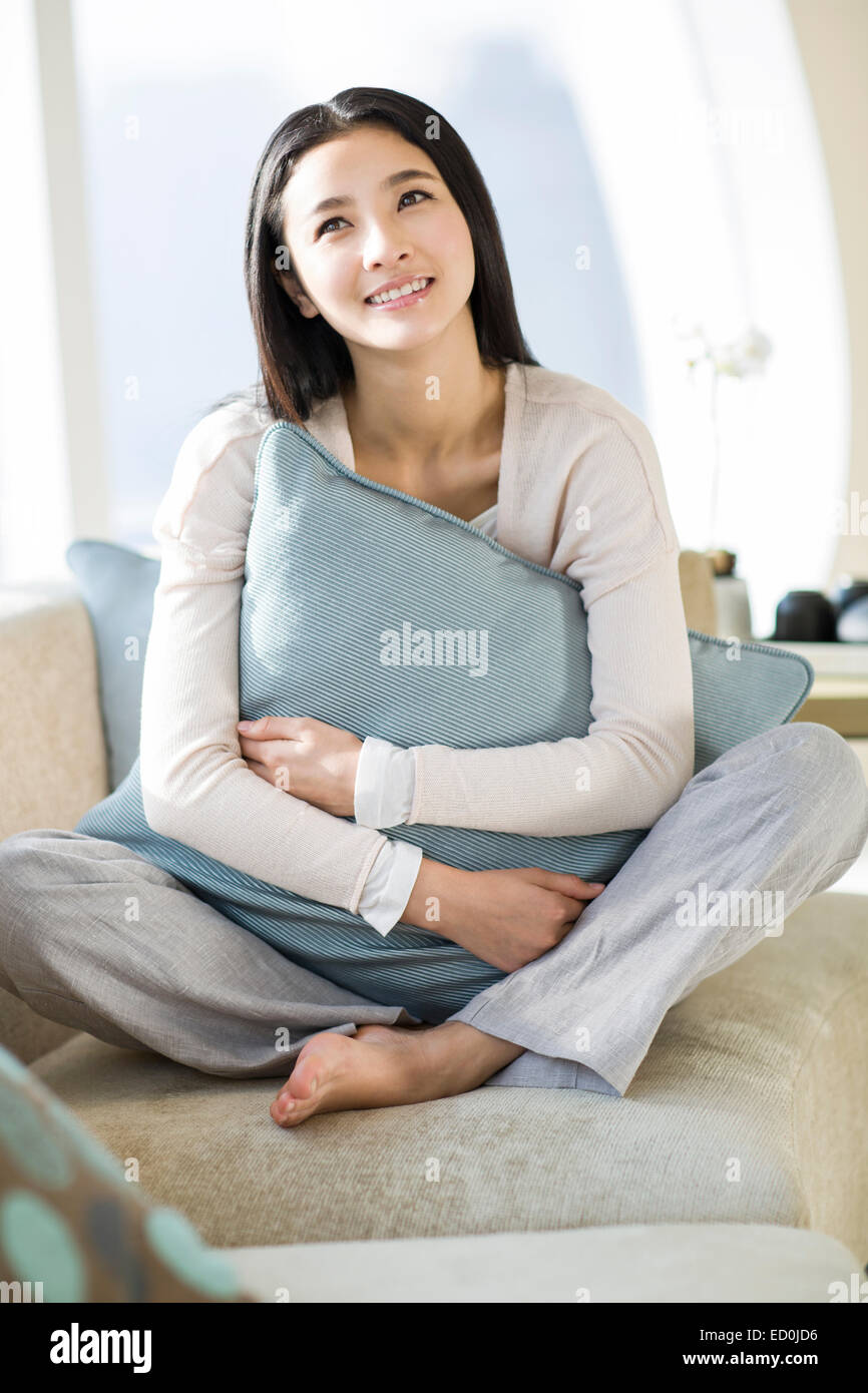 Happy young woman sitting on sofa Stock Photo - Alamy