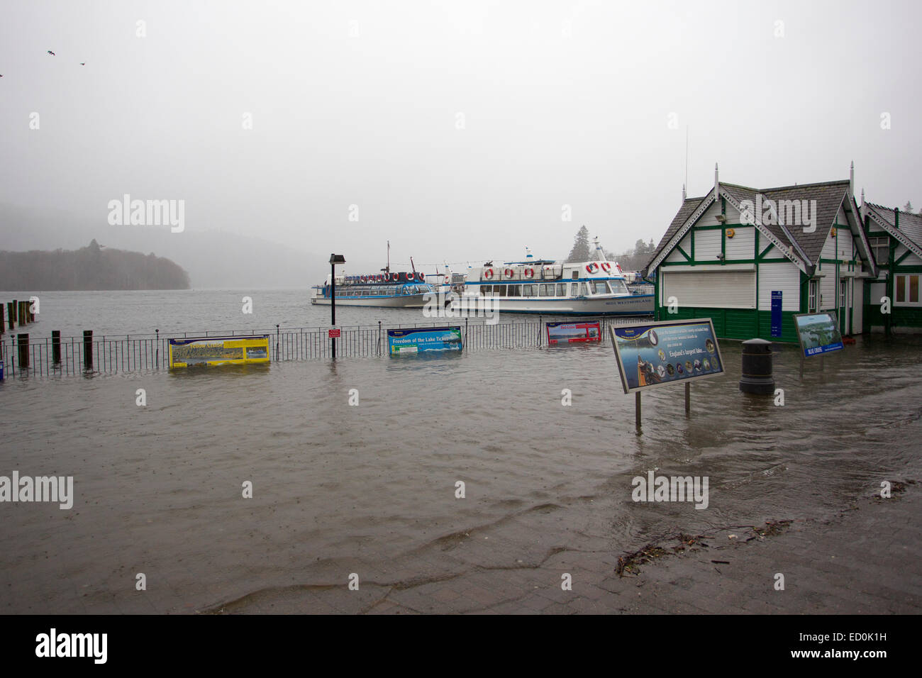 Bowness on Windermere Cumbria UK 23 December 2014. UK Weather: Lake Windermere flooding over at Bowness Bay .Boats still running as tourists brave the weather. Main Ticket office & Cafe are expected to be flooded by the end of the day as the lake rises Credit:  Gordon Shoosmith/Alamy Live News Stock Photo