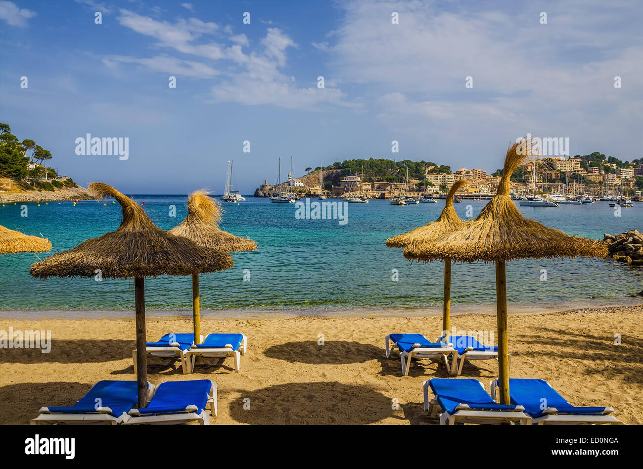 Tropical lounge chairs and umbrellas on a sandy resort beach in Port de Soller, Mallorca, Spain. Stock Photo